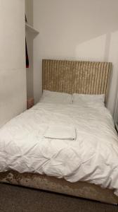 uma cama com lençóis brancos e uma cabeceira em madeira em 68 Halsbury Road em Liverpool