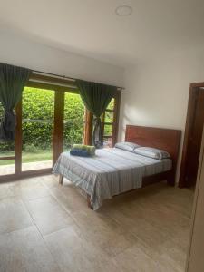 um quarto com uma cama e uma grande janela em Finca Hotel Casa Lupe En Santa Elena em El Cerrito
