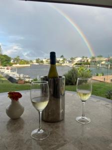 two glasses of white wine on a table with a bottle of wine at Waterfront BNB in Gold Coast
