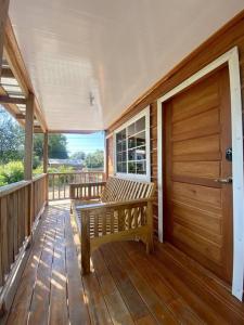 una veranda in legno con panchina e porta di Cashew Tree Cabana - Small Cosy, Close to the Beach. a Placencia