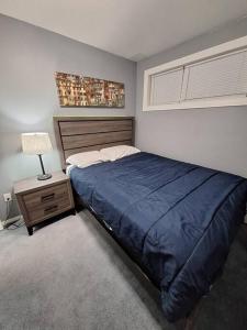 ein Schlafzimmer mit einem Bett mit einer blauen Decke und einer Lampe in der Unterkunft 1-Bedroom Basement Suite in Yellowknife