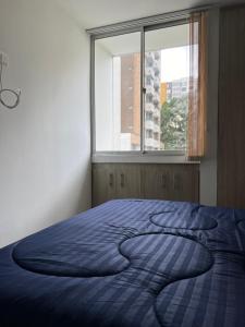 uma cama num quarto com uma grande janela em Lujoso apartamento central y moderno em Manizales