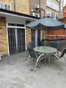 Stylish entire 2bed apartment في لندن: طاولة وكراسي مع مظلة على الفناء