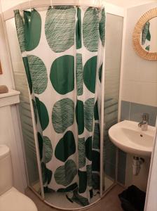 La salle de bains est pourvue d'un rideau de douche avec des feuilles vertes. dans l'établissement "La Terrasse de la mer 8" -Climatisation-Wifi-BBQ -Piscine-Parking, à Begur