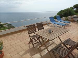 d'une table et de chaises en bois sur un balcon donnant sur l'océan. dans l'établissement "La Terrasse de la mer 8" -Climatisation-Wifi-BBQ -Piscine-Parking, à Begur