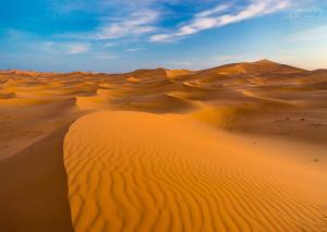 un désert avec des dunes de sable et un horizon dans l'établissement Zaila Erg Chigaga Luxury Camp, à M'Hamid El Ghizlane