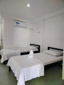 two beds with white sheets in a room at Lang2 place in Coron