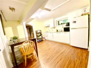 uma cozinha com uma mesa de madeira e um frigorífico branco em Cozy Home near Eglinton west Station Toronto! em Toronto