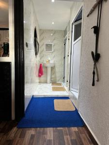 bagno con tappeto blu sul pavimento di Dinosaur Anza Surf House ad Agadir
