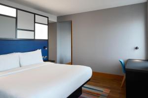 a bedroom with a white bed and a desk and window at Aloft London Excel in London