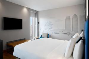 a bedroom with a white bed and a flat screen tv at Aloft London Excel in London