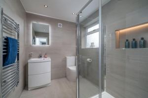 a bathroom with a toilet and a glass shower at Deluxe House W/Parking & Garden Near Wembley - Sleeps 8 in Harrow Weald