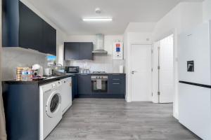 a kitchen with a washing machine and a washer at Deluxe House W/Parking & Garden Near Wembley - Sleeps 8 in Harrow Weald