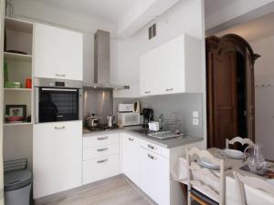 a white kitchen with white cabinets and a table at Appartement Bagnères-de-Luchon, 2 pièces, 4 personnes - FR-1-313-230 in Luchon