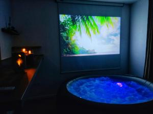 a tv screen with a blue tub in a room at Le nid de l'Almont jacuzzi privatif, private jacuzzi Hot Tub near Olympic Games MELUN in Melun