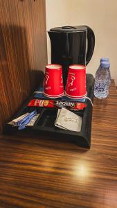 a tray with two red cups on a table at هوتيل القصيم 2 للشقق الفندقية in Buraydah