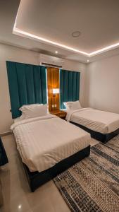 two beds in a hotel room with two at هوتيل القصيم 2 للشقق الفندقية in Buraydah