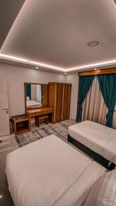 a hotel room with two beds and a mirror at هوتيل القصيم 2 للشقق الفندقية in Buraydah
