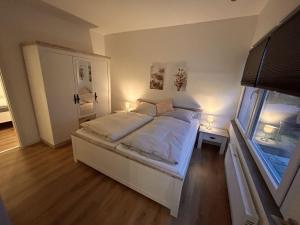 1 dormitorio con cama blanca y ventana en Renoviertes Ferienhaus in Husen mit Terrasse und Sauna, en Lichtenau