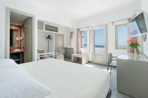 a white bedroom with a white bed and a desk at Krokos Villas in Imerovigli