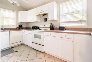 una cocina blanca con armarios blancos y electrodomésticos blancos en The Yellow Bungalow, en Savannah
