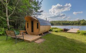 a wooden cabin with a bench next to a lake at Four Season Waterfront Muskoka Retreat in Bracebridge
