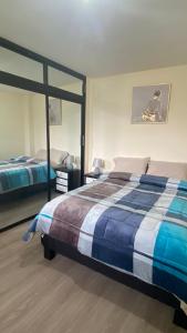 a bedroom with a bed with a blue and white blanket at Apto. a una cuadra del Terminal in Quito