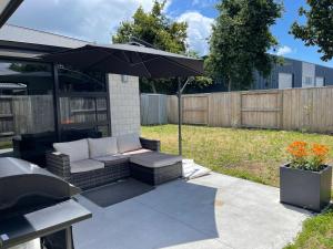 a patio with a couch and an umbrella at Place for a Holiday in Papamoa