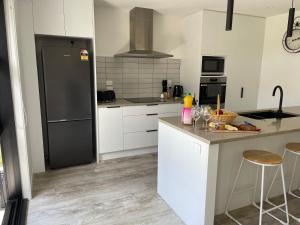 a kitchen with white cabinets and a black refrigerator at Place for a Holiday in Papamoa