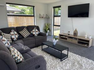 a living room with a couch and a flat screen tv at Place for a Holiday in Papamoa