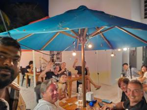 蒂夫斯的住宿－Nirili Villa，一群人坐在桌子上,在伞下