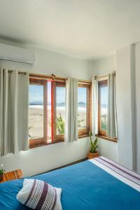 a bedroom with a bed with blue sheets and windows at Hotel Sanmara in La Sabrosa