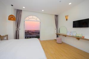 a bedroom with a bed and a tv and a window at Lily House Hotel Phu Quoc in Phú Quốc