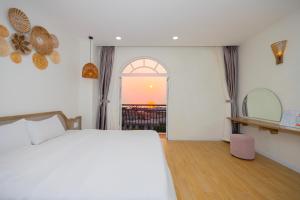 富國的住宿－Lily House Hotel Phu Quoc，一间卧室设有一张床和一个享有日落美景的窗户