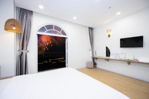 a bedroom with a large bed and a window with a fireworks display at Lily House Hotel Phu Quoc in Phú Quốc