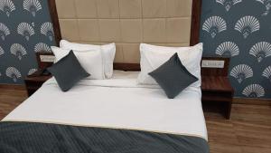 a large bed with white sheets and black pillows at Hotel Amrit Resort in Alwar
