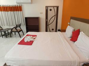 Una cama blanca grande con una toalla roja. en Super OYO Happy Grand Hotel, en Vijayawāda