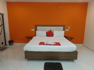 a bedroom with a large bed with an orange wall at OYO Happy Grand Hotel in Vijayawāda