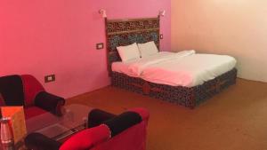 a bedroom with a bed with pink walls and red chairs at Ishaan Resort in Manāli