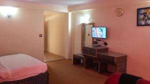 Ishaan Resort في مانالي: غرفة نوم بسرير ومكتب مع تلفزيون
