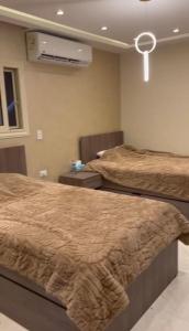 two beds in a bedroom with a air conditioner at شقة فندقية فاخرة in Al Ma‘şarah