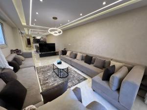 un ampio soggiorno con divani e televisore di شقة فندقية فاخرة a Al Ma‘şarah