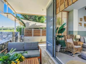 a living room with a couch and chairs on a balcony at Villa Salvia - Country style luxury & a captivating poolscape in Áyiai Paraskiaí