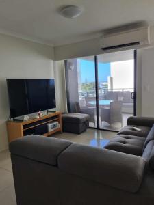 a living room with a couch and a flat screen tv at Private Bedroom and Bathroom in a shared Apartment in Gold Coast