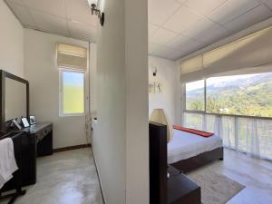 a bedroom with a bed and a desk and a window at Dream Hills Villa, Nillambe Kandy in Kandy