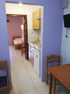 パノルモス・カリムノスにあるClimbing House Apartmentsの紫の壁のキッチン(テーブル、テーブル、椅子付)