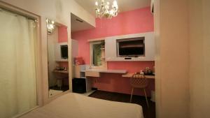 sypialnia z różowymi ścianami, łóżkiem i telewizorem w obiekcie Premier Exclusive Guesthouse w mieście Yogyakarta