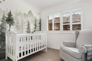 ein Kinderzimmer mit einem Kinderbett und einem Weihnachtsbaum-Wandbild in der Unterkunft Stylish Beachside Sanctuary, steps to the beach in Sydney