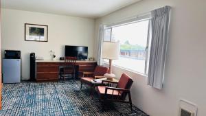 ein Hotelzimmer mit einem Schreibtisch, Stühlen und einem Fenster in der Unterkunft Curly Redwood Lodge in Crescent City