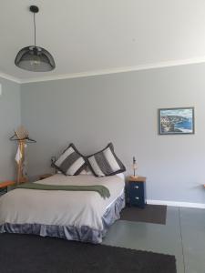 a white bedroom with a bed with black pillows at The Red Shed in Matamata